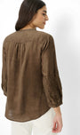 Woman wearing a brown blouse with intricate detailing on a white background
