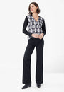 Front view a black and white geometric patterned top with long sleeves, paired with black trousers.