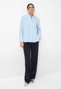 Woman wearing a light blue shirt and dark pants Front view.