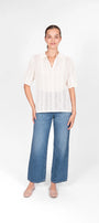 Woman wearing a white Polo Top and blue jeans .