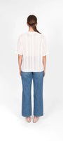 Person wearing a white blouse and blue jeans.