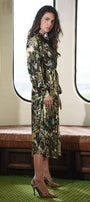 Woman in a floral dress standing in a train carriage with large windows.