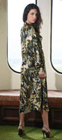 Woman wearing a floral dress standing in a train car with large windows.