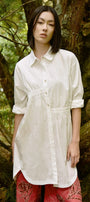 Woman wearing a white shirt and red pants standing in a forest setting
