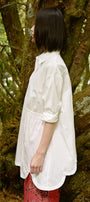 Person wearing a white shirt and red pants standing in a forest