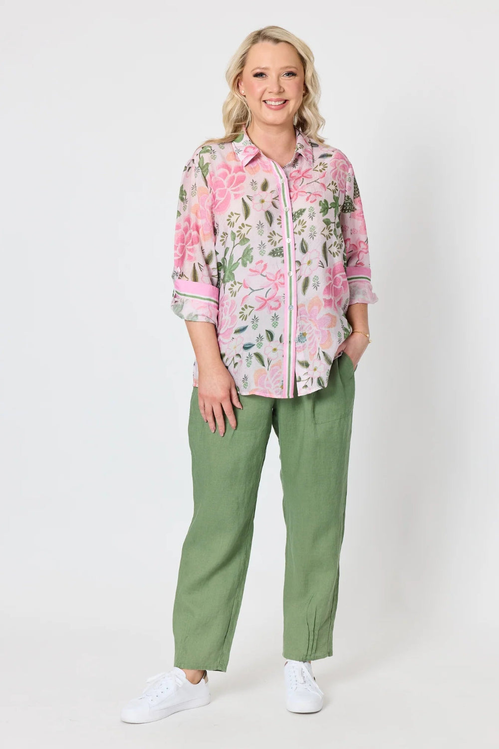 pink and green floral print button up shirt with three quarter sleeves, paired with sage green pants and white sneakers,
