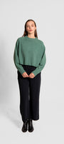 Person wearing a green sweater and black pants.