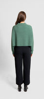 Person wearing a green sweater and black pants .