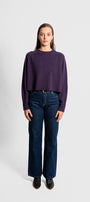 Person wearing a purple sweater and blue jeans 