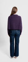 Person wearing a purple sweater and dark blue jeans.