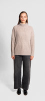 Person wearing a beige sweater and gray pants ,