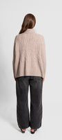 Person wearing a beige sweater and dark pants.