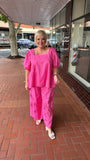 Person wearing a pink pant standing on a brick sidewalk with a building in the background