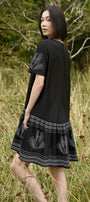 Woman wearing a black dress with white patterns in a natural setting