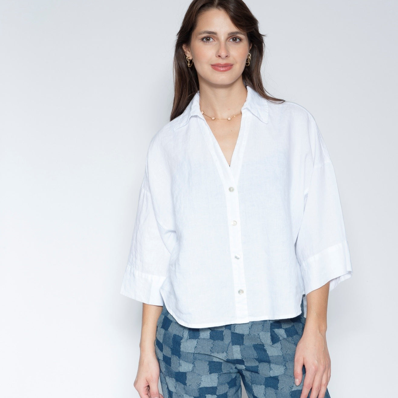 Front View white short sleeve button up shirt with three quarter sleeves and blue patterned trousers.