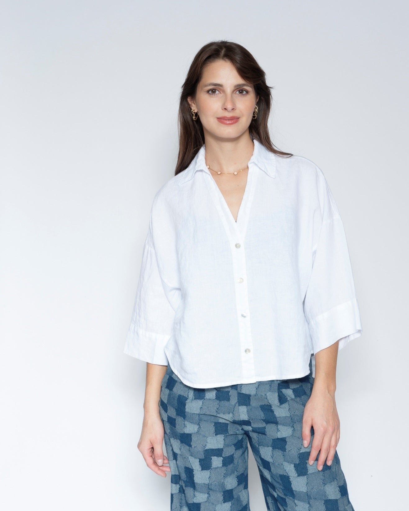 Front View white short sleeve button up shirt with three quarter sleeves and blue patterned trousers.