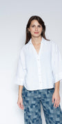 Front View white short sleeve button up shirt with three quarter sleeves and blue patterned trousers.