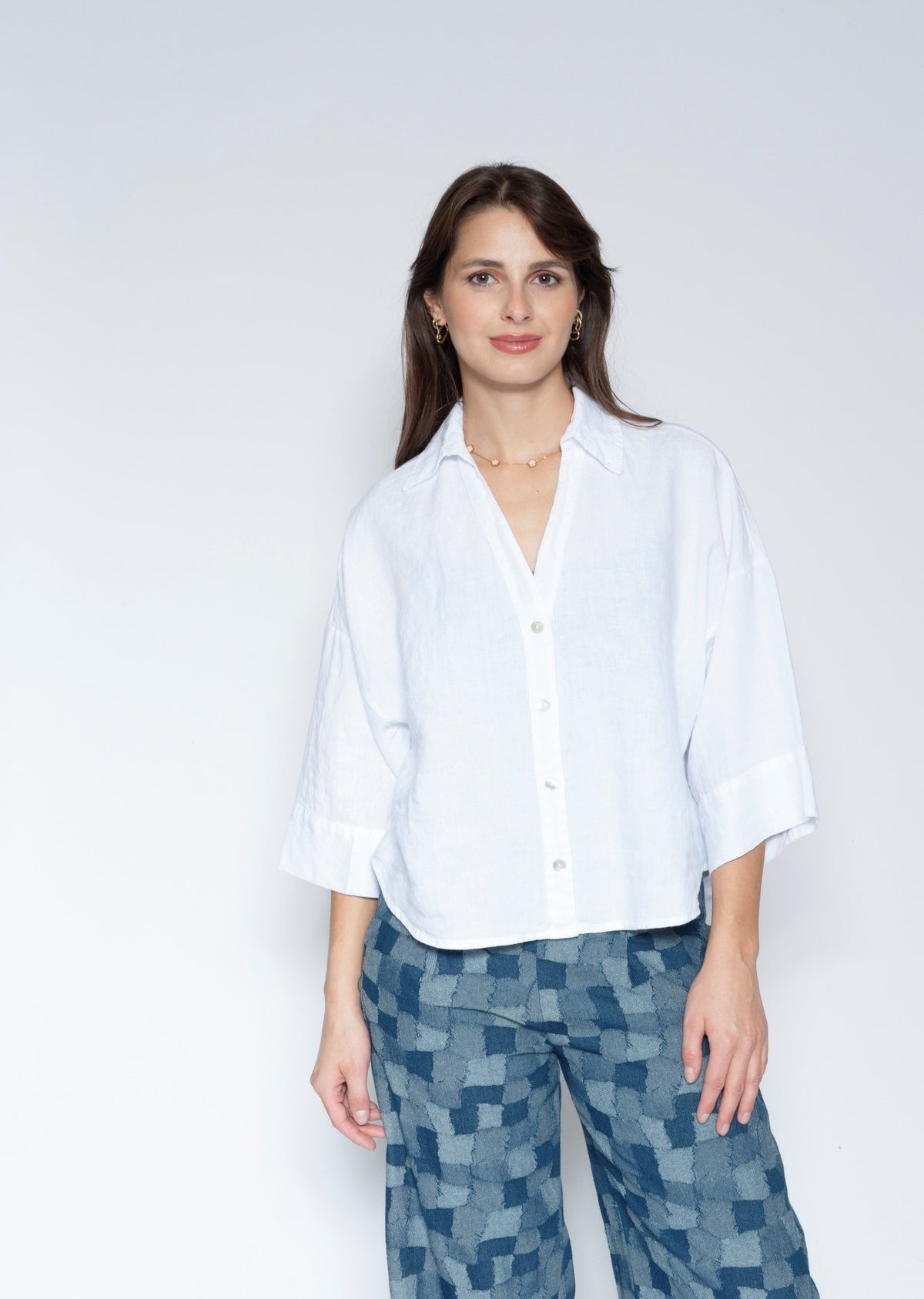 Front View white short sleeve button up shirt with three quarter sleeves and blue patterned trousers.