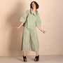  sage green two piece outfit consisting of a cropped, short sleeved button up top with pleated details and matching wide leg cropped pants, styled with black platform sandals.