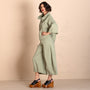 Side view  sage green two piece outfit consisting of a shor sleeve button up shirt and matching wide leg cropped pants, styled with black platform sandals.