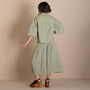 Back view a sage green two piece outfit consisting of a short sleeve cropped shirt and matching wide leg cropped pants, paired with black wedge sandals.