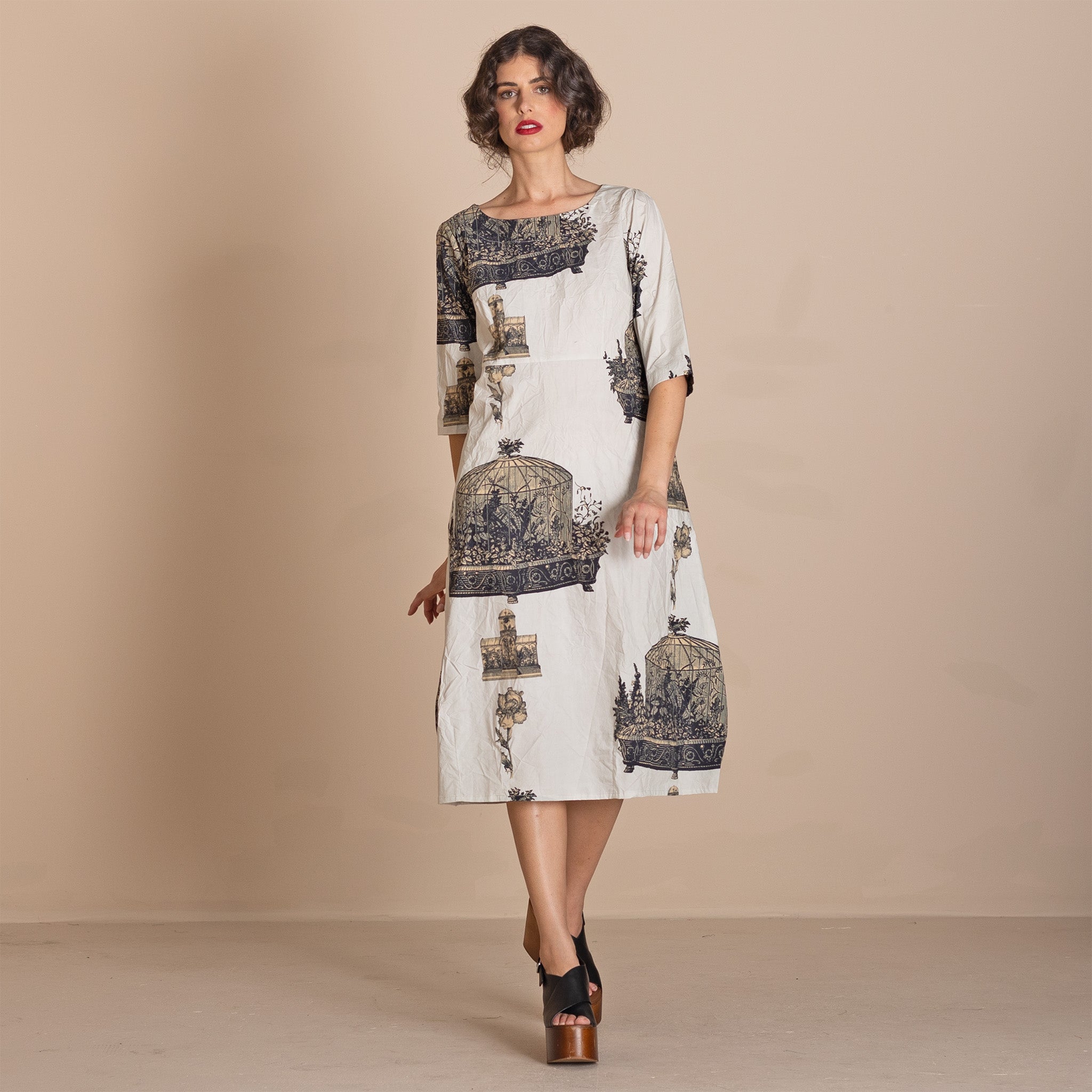  knee-length white dress with a dark blue and gray birdcage pattern, featuring three quarter sleeves and a boat neckline.
