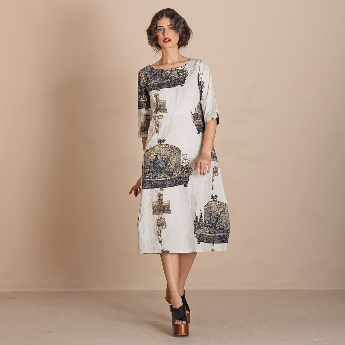  knee-length white dress with a dark blue and gray birdcage pattern, featuring three quarter sleeves and a boat neckline.