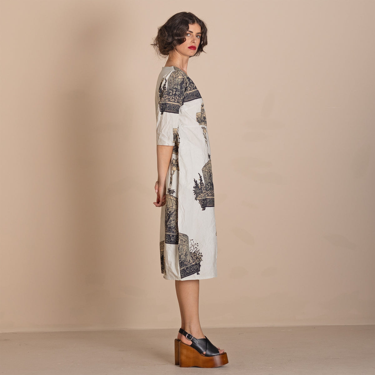 knee length white dress with a dark navy blue scenic print, styled with black platform sandals.