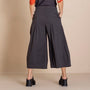 back  view  black wide leg cropped pants, a dark top with orange patterned sleeves, and black shoes.
