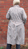 Person wearing a checkered coat standing against a brick wall.