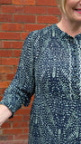Person wearing a dark blue patterned dress against a brick wall.