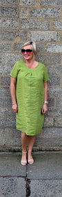 Front View lime green short sleeve midi dress, pink sunglasses, and pink sandals .