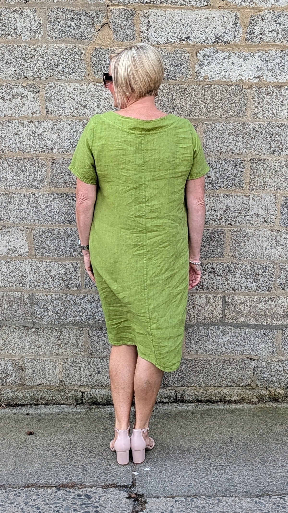 back view of a short sleeved lime green midi dress and light pink heels.