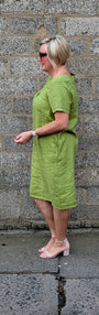Side view of a short sleeved olive green dress and light pink high heels.