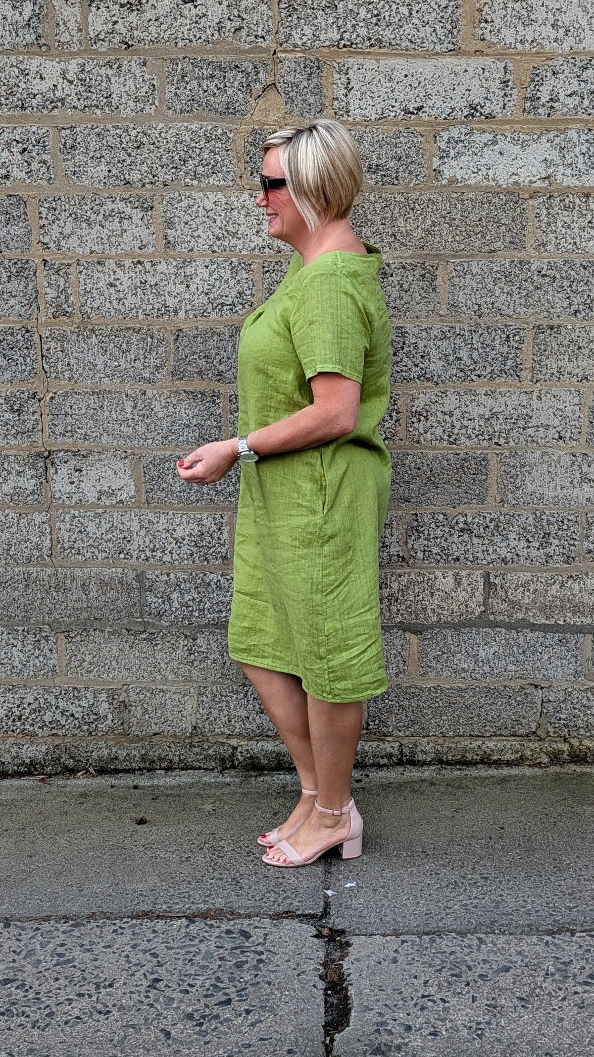 Side view of a short sleeved olive green dress and light pink high heels.