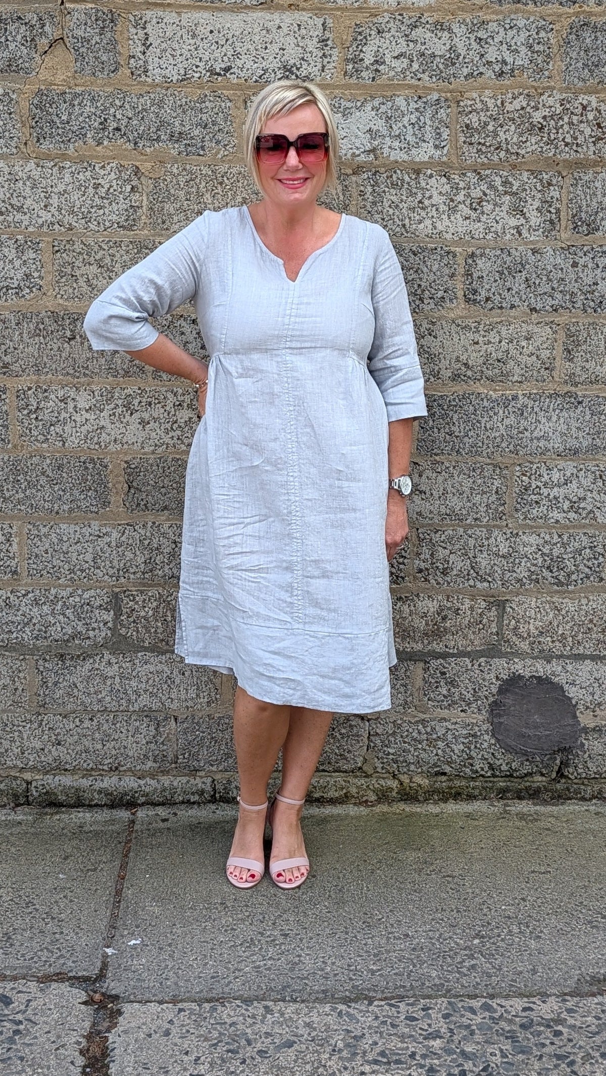 Front View of a light grey linen blend midi dress and pink sandals .