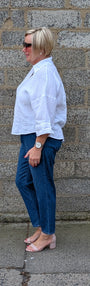 Side View of a white button up shirt, dark blue jeans, and light pink heeled sandals.