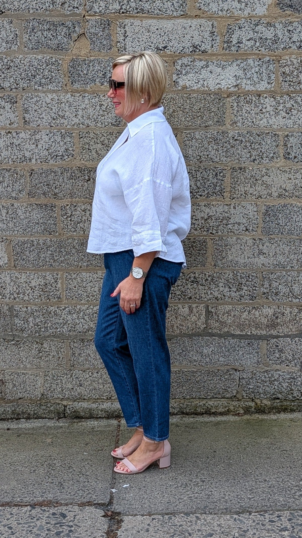 Side View of a white button up shirt, dark blue jeans, and light pink heeled sandals.