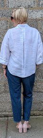 Back View of a white button up shirt, dark blue jeans, and pink flat shoes.