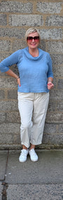 Front View  a light blue cowl neck knit top, cream colorued cropped trousers, white sneakers.