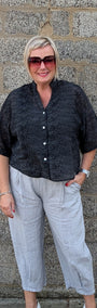 Front View of  a black short sleeve button up shirt, light gray cropped trousers, and white pointed toe heels.