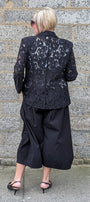  black lace blazer, black cropped wide-leg pants, and black pointed flats.