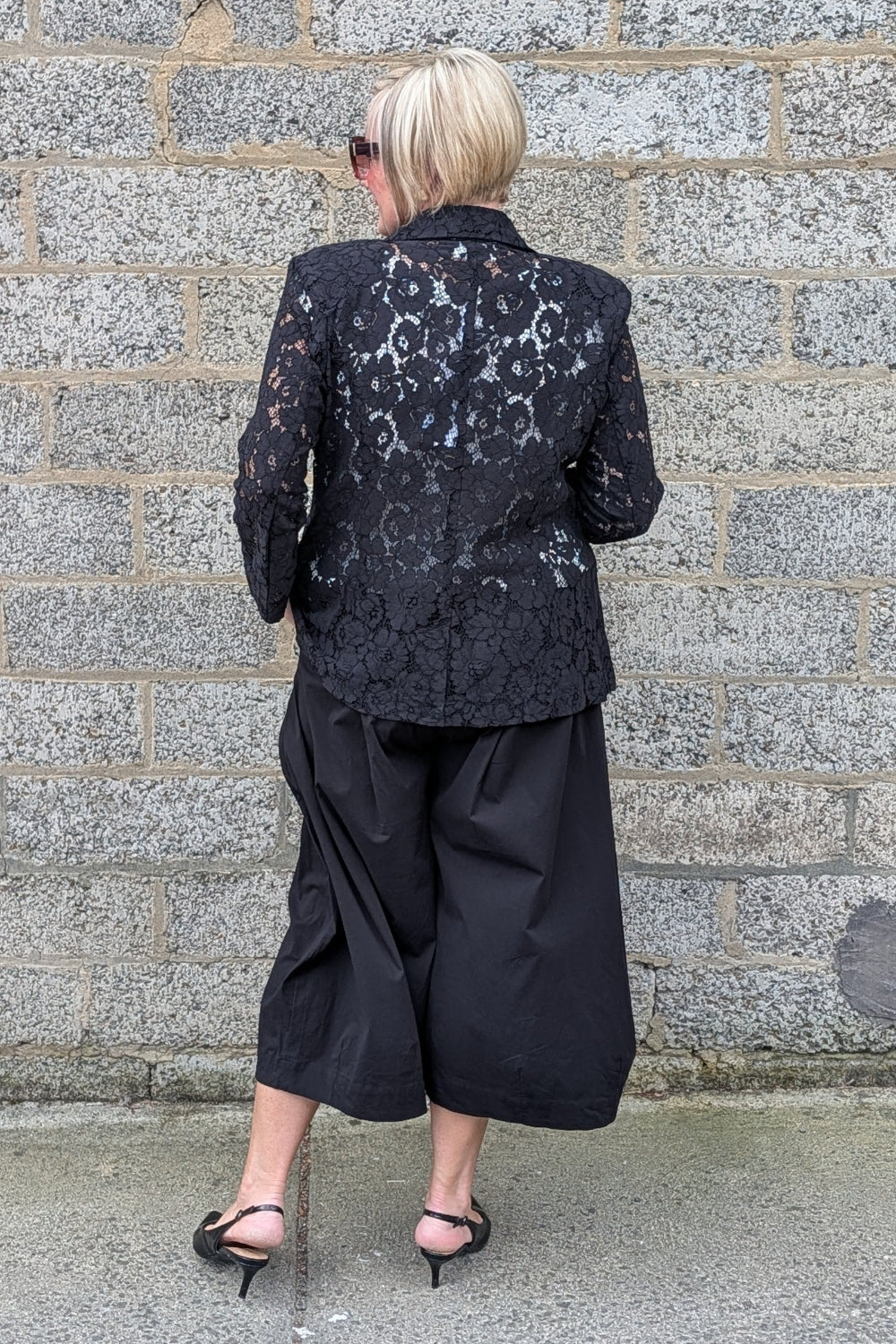  black lace blazer, black cropped wide-leg pants, and black pointed flats.