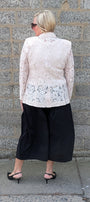 Lace Blazer by Two-Ts in Straw back view lstraw lace  jacket and black wide-leg cropped pants against a gray stone wall.