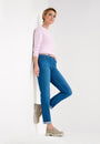 Side view  pink long sleeve top and blue jeans with a high waist and slim fit. She is also wearing a pair of tan shoes.