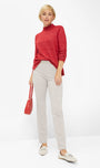 Front viewa red sweater and beige pants holding a red handbag .