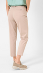 Back view   beige colored pants with a tapered leg and a wide waistband, paired with a light green blouse and tan flat shoes.