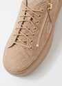Beige sneaker with woven pattern and gold zipper on a white background
