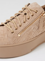 Beige sneaker with gold zipper on a light gray background
