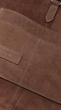 Close-up of a brown leather bag with a visible brand logo.